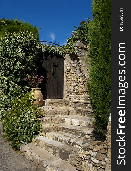 A sunny and ancient entrance with flower pot and greenery