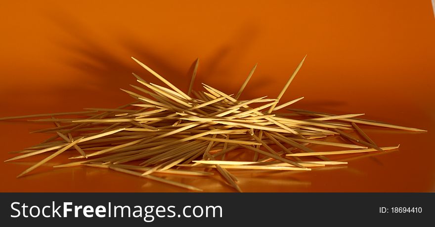 Pile of wooden toothpicks on yellow background. Pile of wooden toothpicks on yellow background
