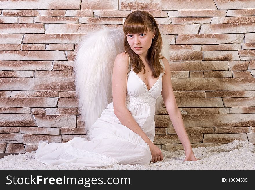 Angel girl on brick wall background. Siting poses