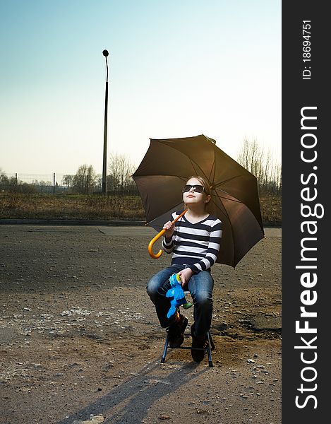 Little girl in sunglasses and with umbrella sitting. Outdoor portrait. Little girl in sunglasses and with umbrella sitting. Outdoor portrait