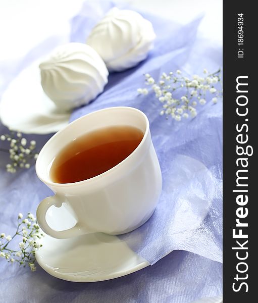 Cup of tea, zephyr and flowers on blue background