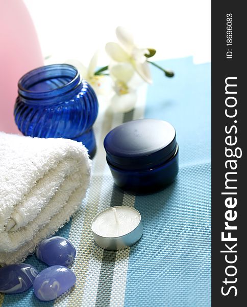 Spa composition of towel, stones and candle on blue