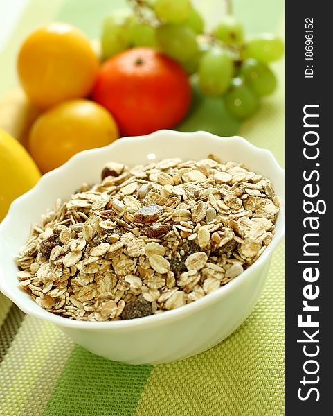 Muesli of oats with raisin and fresh fruit on green background