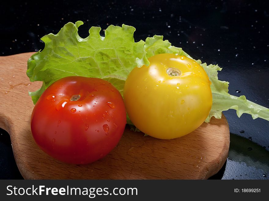 Ripe tomatoes with lettuce on cutting board