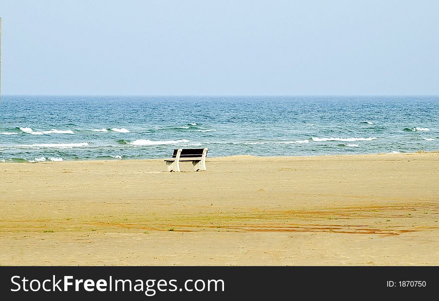 Solitary bench on an uncluttered beach, white caps on the waves. Solitary bench on an uncluttered beach, white caps on the waves.