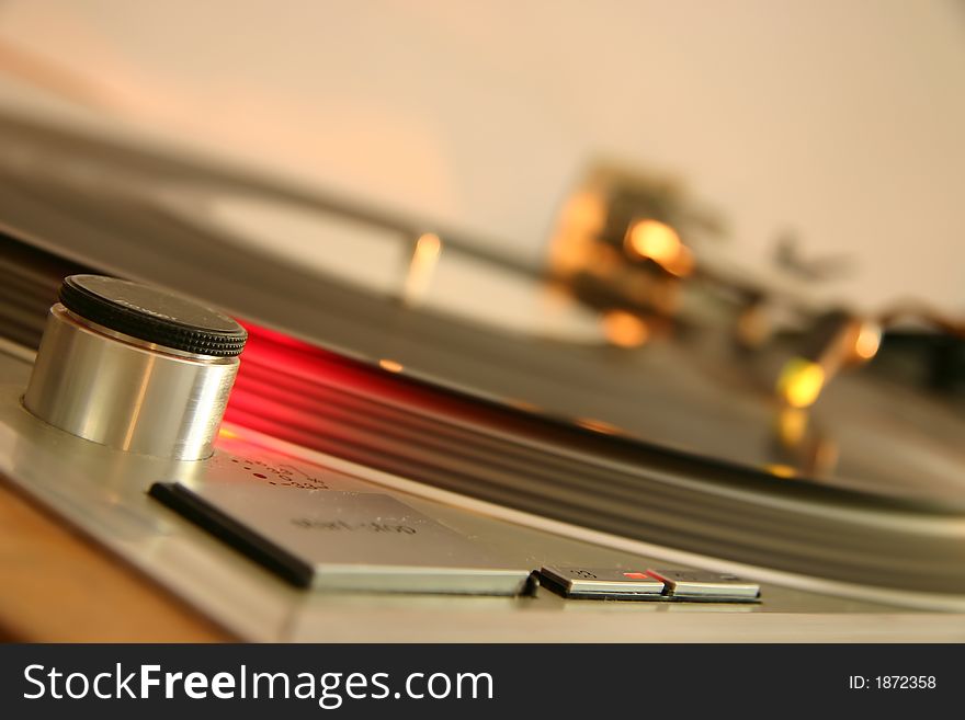 Red strobe light on a silver DJ turntable, with spinning white label record, platter and light