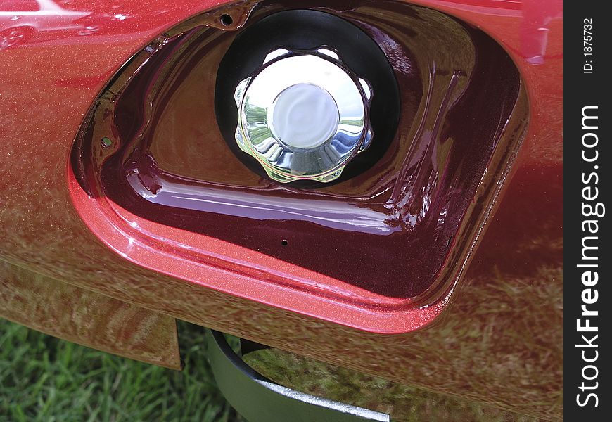 Fuel filler cap in chrome in fender of red car;  missing cover. Fuel filler cap in chrome in fender of red car;  missing cover