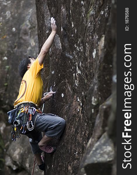 Asian rock-climber reacing for handhold. Asian rock-climber reacing for handhold