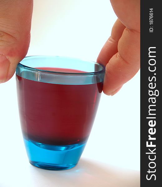 Blue tot glass being picked up by hand