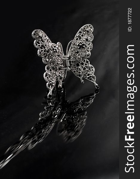 Decorative butterfly hairpin on a reflective background