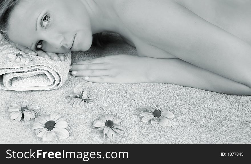 Portrait of a fresh and beautiful blond woman on a towel with flowers. Portrait of a fresh and beautiful blond woman on a towel with flowers