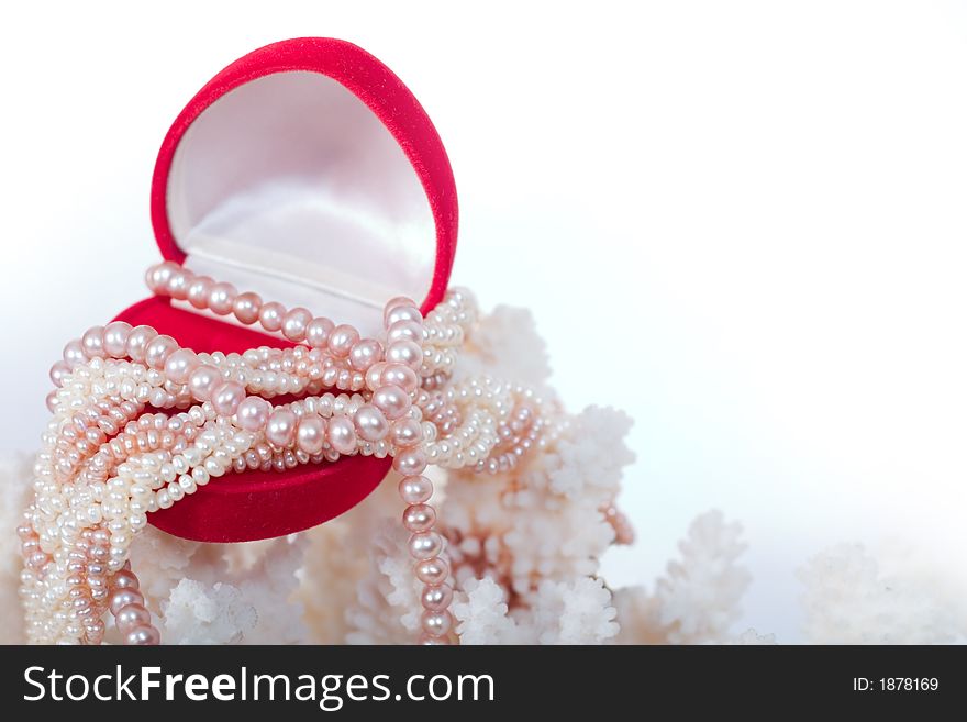 Corals and heart-shaped red box with shiny pearl necklace. With copy space on white background. Corals and heart-shaped red box with shiny pearl necklace. With copy space on white background.