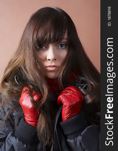 Portrait of the cold girl in a black jacket and red gloves