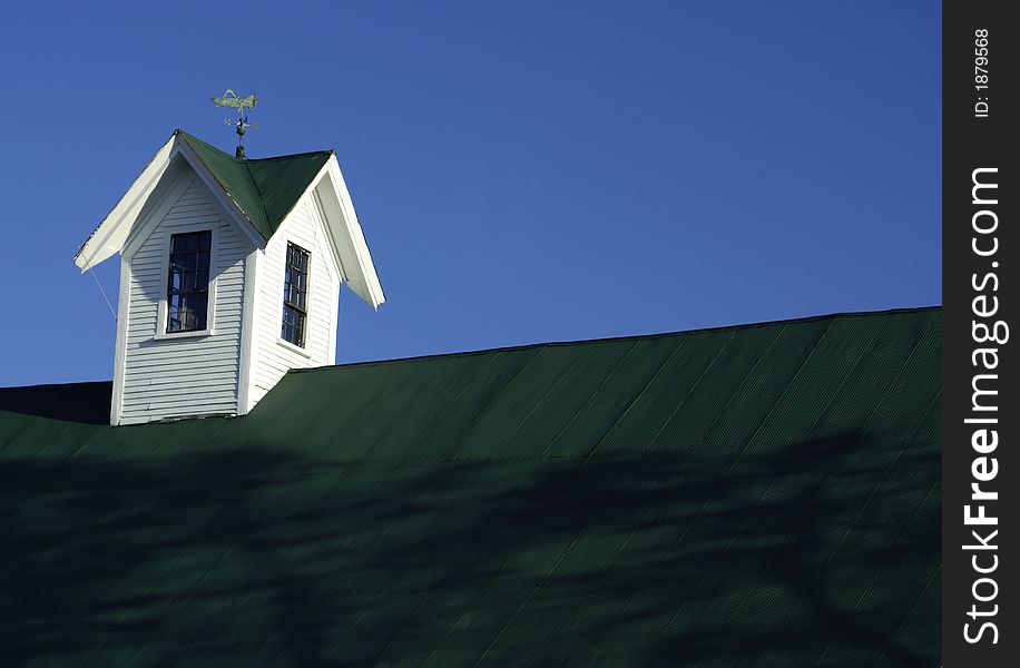 The rooftop of an old barn with a weathervane in the shape of a cricket. The rooftop of an old barn with a weathervane in the shape of a cricket