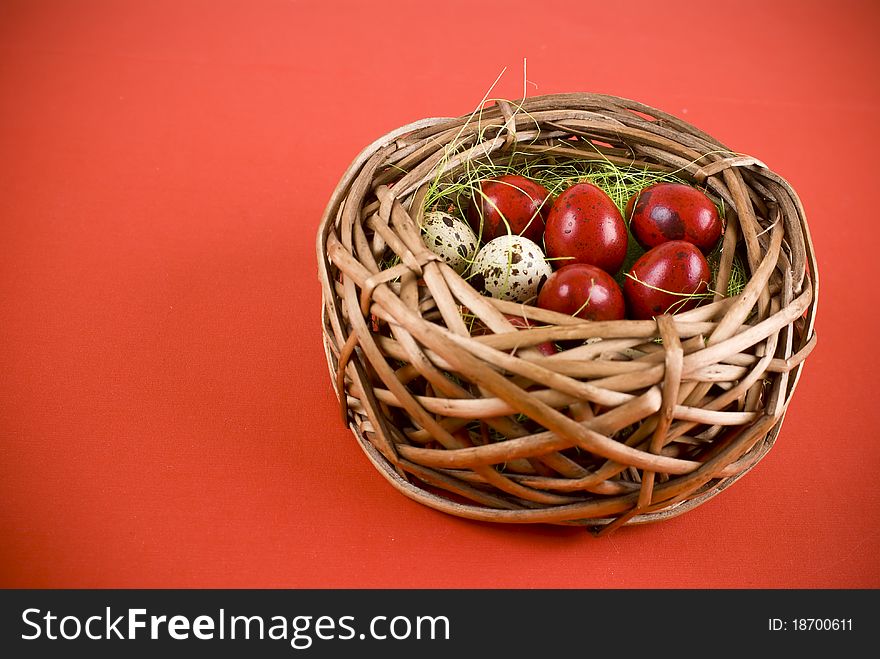 Easter eggs in wicker basket on red background