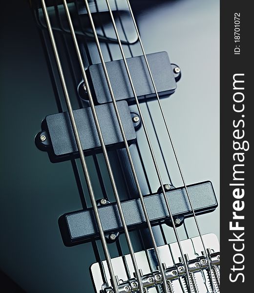 Closeup of black five cords electric bass and pickups. Vertical shape, studio shot. Closeup of black five cords electric bass and pickups. Vertical shape, studio shot