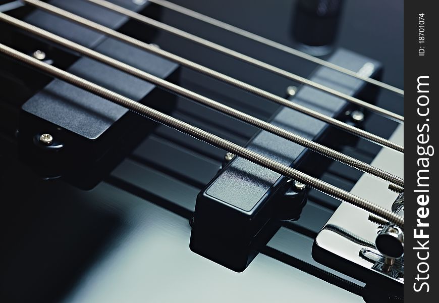 Closeup of black five cords electric bass and pickups. Horizontal shape, studio shot. Closeup of black five cords electric bass and pickups. Horizontal shape, studio shot
