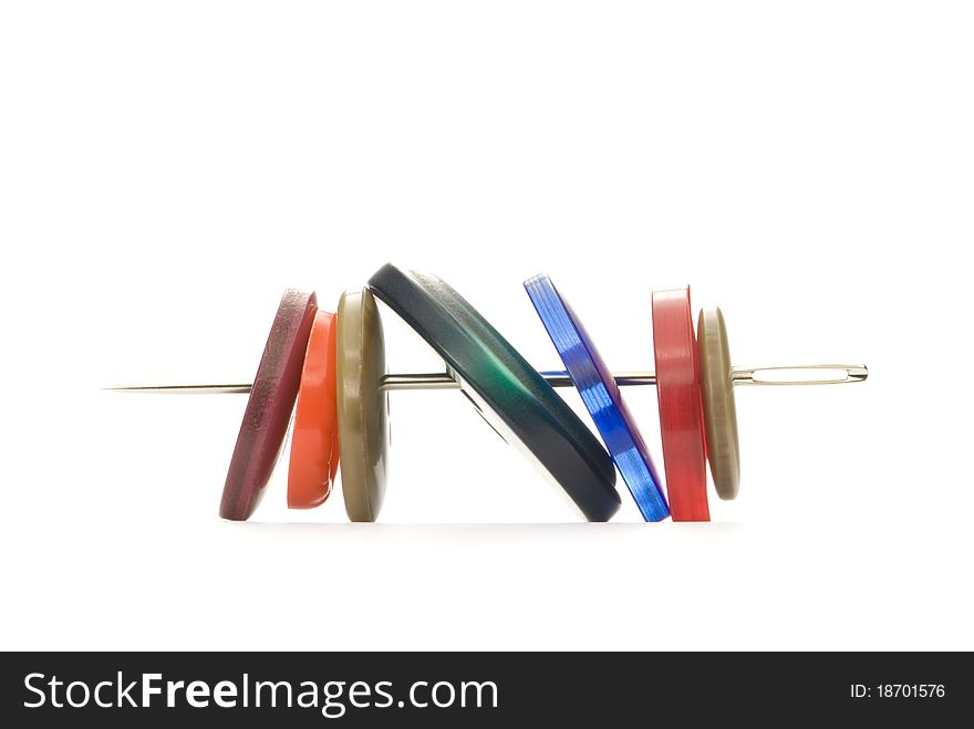 Multi-coloured buttons and needle. Isolated over white. Multi-coloured buttons and needle. Isolated over white.