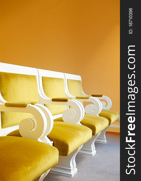 Row of yellow armchairs against a wall. Row of yellow armchairs against a wall.