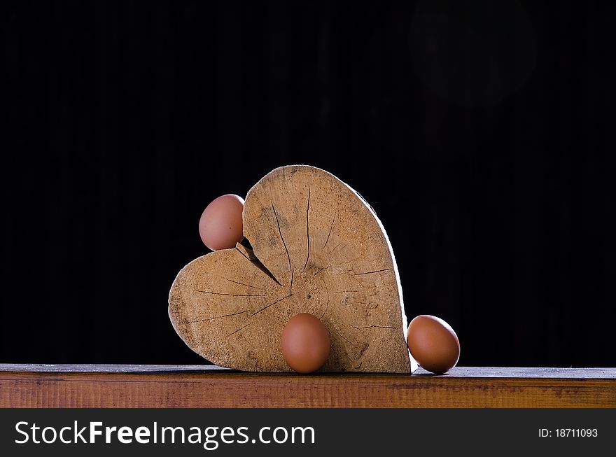 Still life of a wooden heart in the sun and some natural eggs around it. Still life of a wooden heart in the sun and some natural eggs around it.