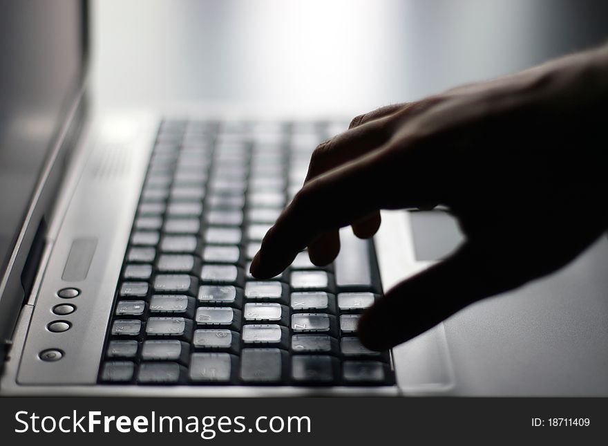 Hand on gray laptop keyboard. Hand on gray laptop keyboard