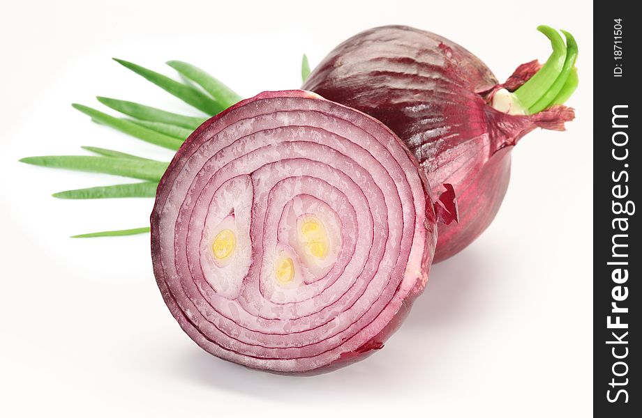 Bulbs of red onion with green leaves on a white background.