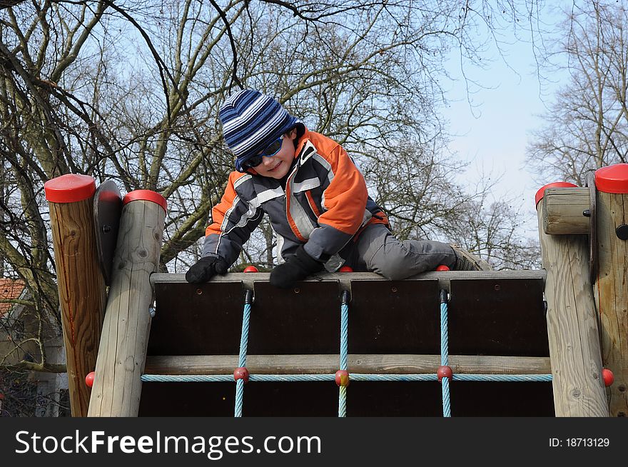 Young smiling boy getting over a barrier, having fun on a playground. Young smiling boy getting over a barrier, having fun on a playground