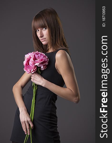 Fashion woman with flowers posing over grey background
