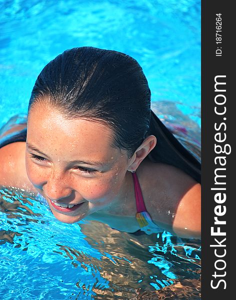 A preteen girl's head and face while in the water of a pool. A preteen girl's head and face while in the water of a pool.