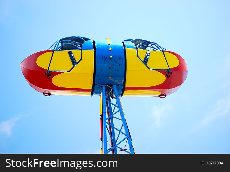 A bright colored amusement ride that is raised high in the sky with colors of red blue and yellow.