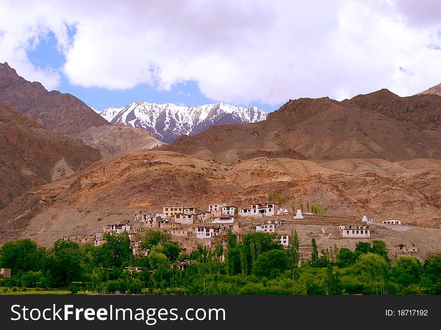 A beautiful scene of a mountain and snow peaks with small houses in a Himalayan region. A beautiful scene of a mountain and snow peaks with small houses in a Himalayan region.