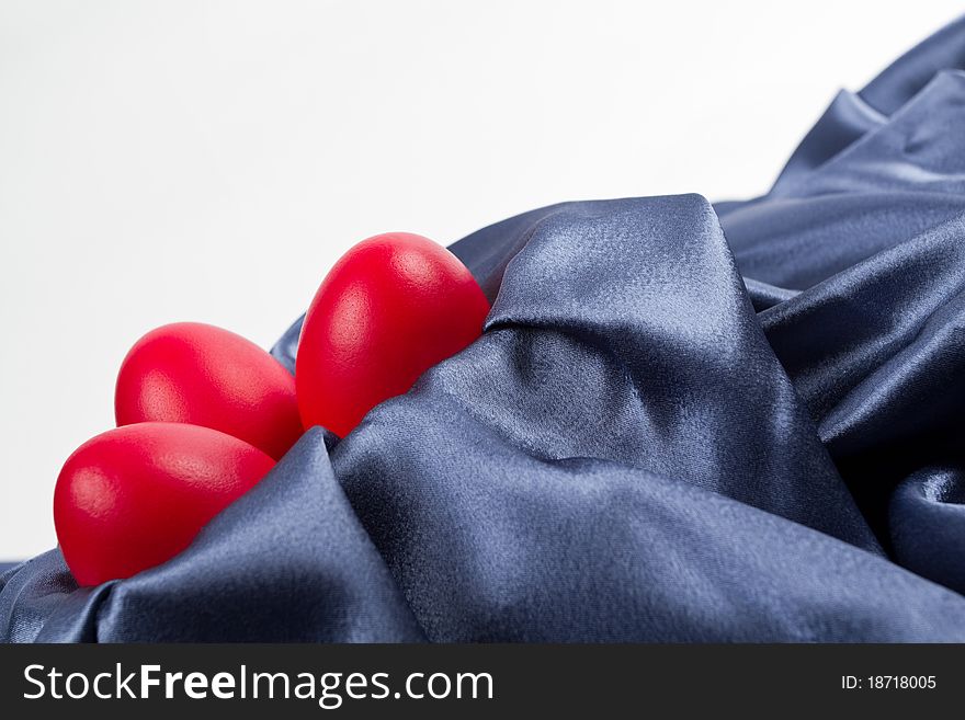 Red Easter eggs on a blue satin textile.