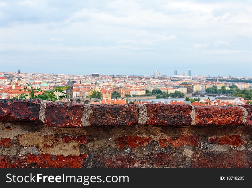 Fragment of old brick wall with old city and sky on background. Fragment of old brick wall with old city and sky on background