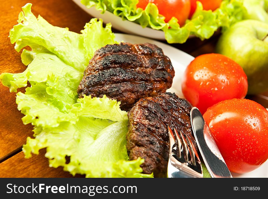 Grilled cutlets with tomatoes and green salad. Grilled cutlets with tomatoes and green salad