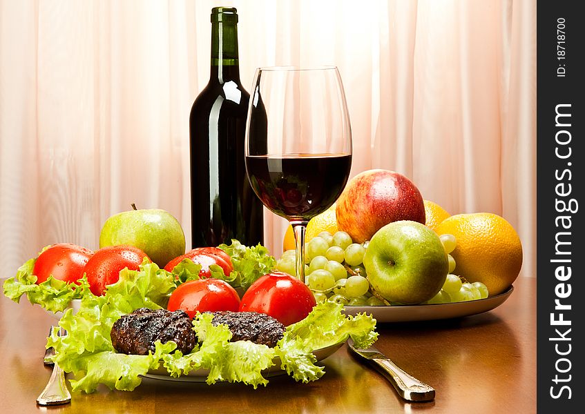 Grilled cutlets with tomatoes, red wine and grapes served on a wooden table. Grilled cutlets with tomatoes, red wine and grapes served on a wooden table