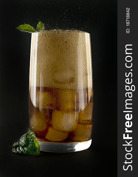 Glass with cola ice and mint on black background. Glass with cola ice and mint on black background.