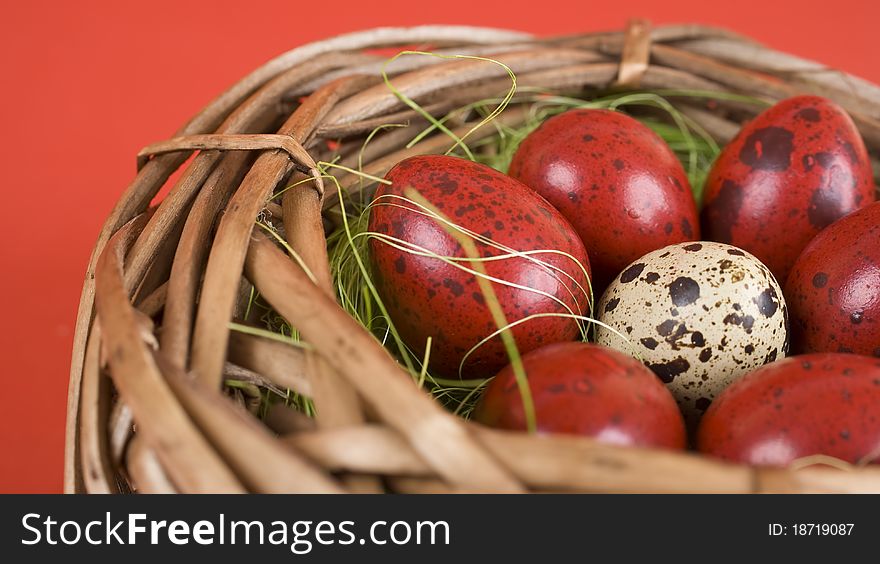 Easter eggs in wicker basket on red background