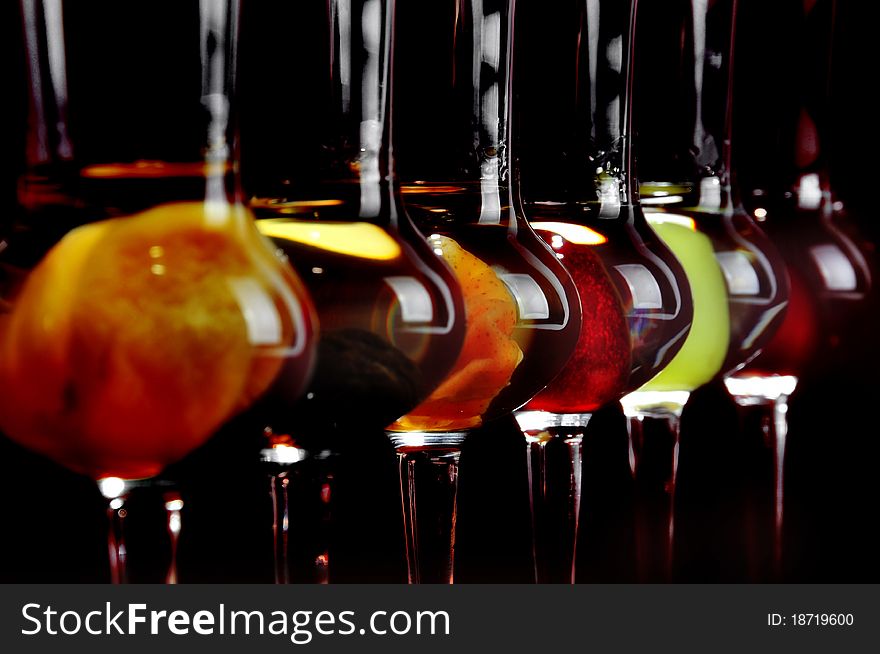 A line of spirits, strong drinks made from different fruits in tall glasses. A line of spirits, strong drinks made from different fruits in tall glasses.
