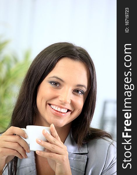 Portrait of a smart young businesswoman reading paper and drinking coffee at office