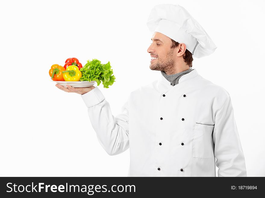 Happy cook holding a plate with vegetables on white background. Happy cook holding a plate with vegetables on white background