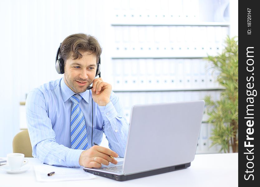 Closeup of a businessman with headset. He is working on laptop
