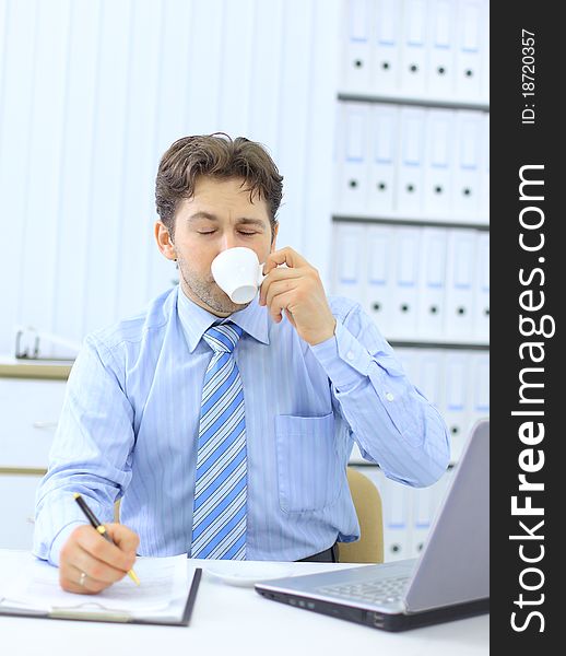 Portrait of a young business executive drinking coffee while looking at the computer