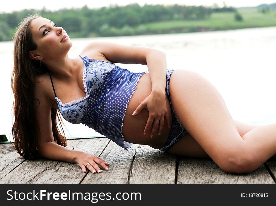 Young pregnant woman at the pier near river