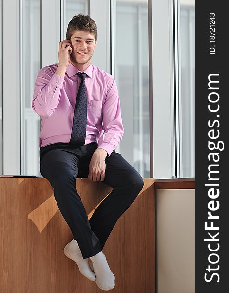 Young business man talk by cellphone over bright window in big hall