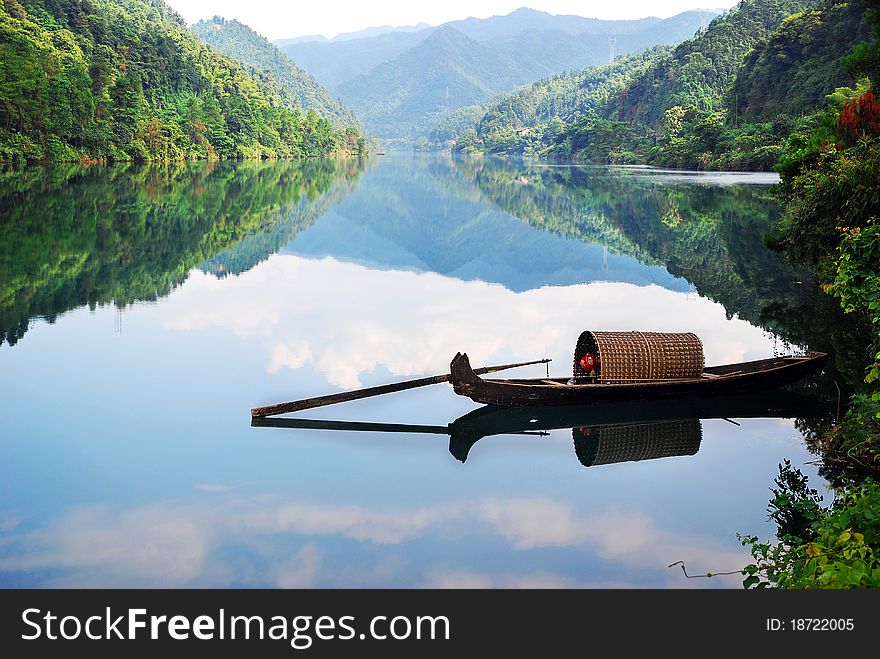 Boat in the river with clear reflection and blue sky.