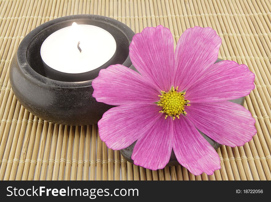 Flower, candle and spa stone on a bamboo mat. Flower, candle and spa stone on a bamboo mat