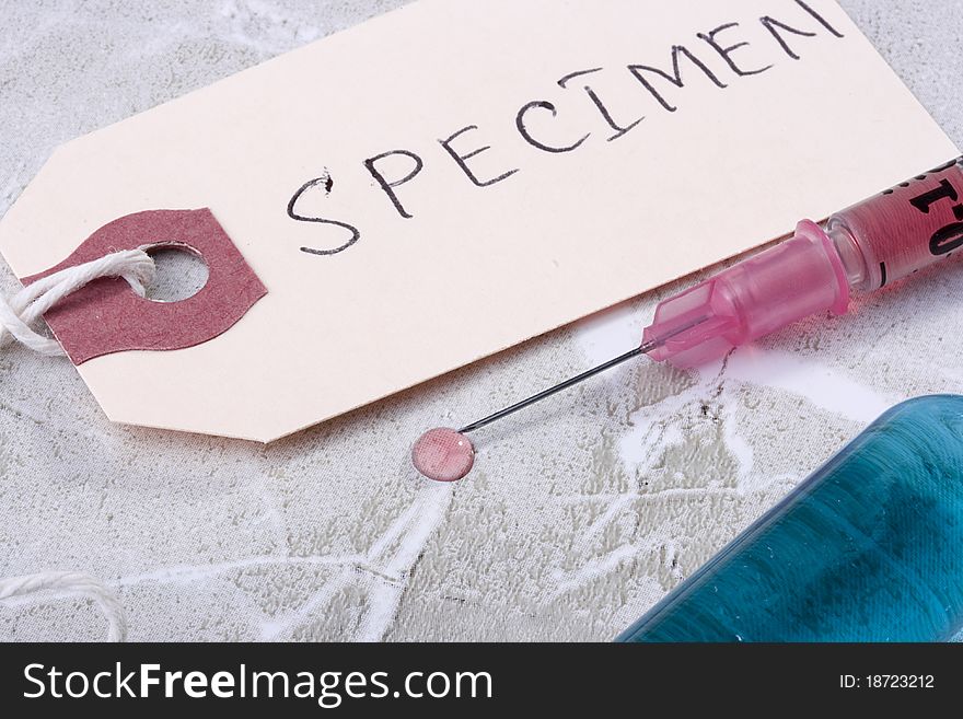 Syringe with pink liquid next to a tag which says Specimen.