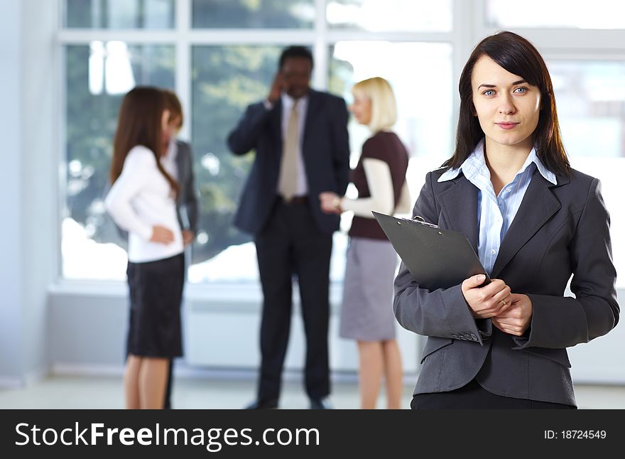 Confident businesswoman with colleagues in the background