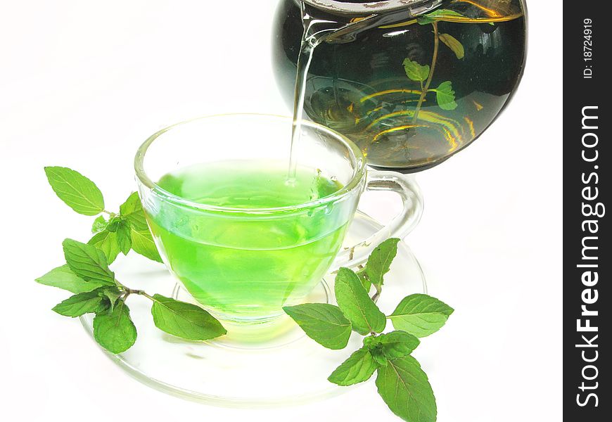Pouring into cup green herbal tea with fresh mint