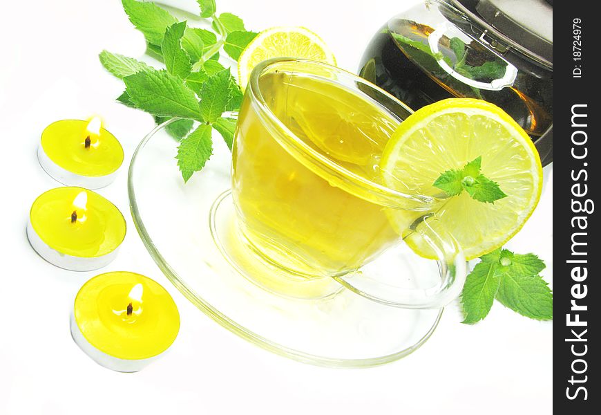 Fruit yellow tea with lemon and fresh mint among scented candles. Fruit yellow tea with lemon and fresh mint among scented candles